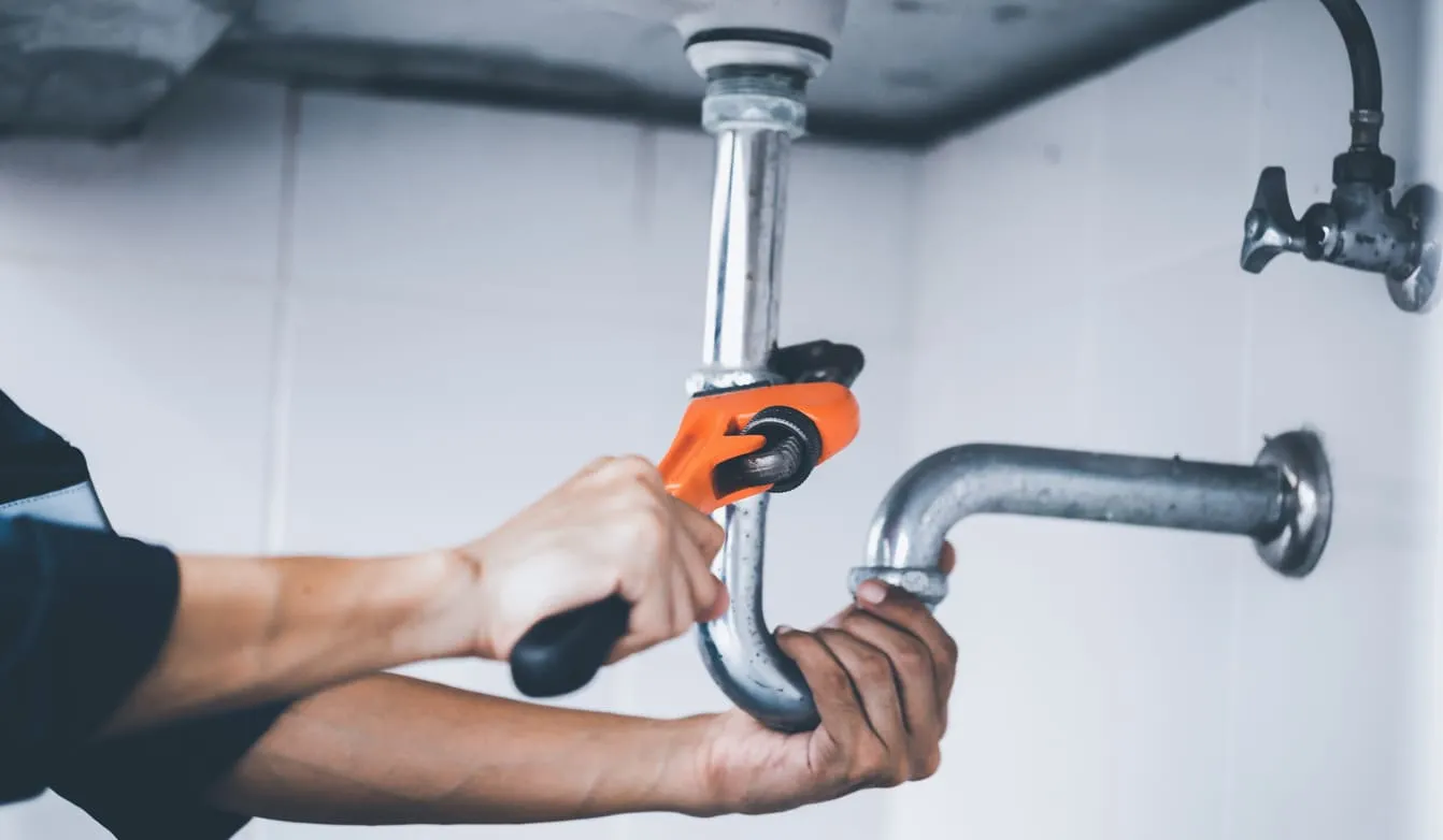Plumber Using Wrench on Bathroom Sink